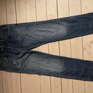 Replay Anbass - Snygga blå jeans från Replay Anbass med en cool slitningseffekt. De har en klassisk femficksdesign och knappgylf. Perfekta för en avslappnad stil med en touch av edge.