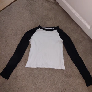 Vit och svart långärmad tröja baseball tee H&M  - En vit och svart långärmad tröja, eller baseball tee från H&M Divided.  Är möjligen lite liten/kort för att vara M