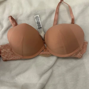 Rostfärgad bh  - Säljer en snygg rostfärgad bh  med spetsdetaljer på sidorna. Bh:n har justerbara axelband och vadderade kupor för extra stöd. Perfekt för en bekväm och stilren look.