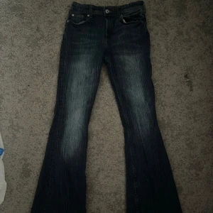 Mörkblå bootcut jeans - Snygga mörkblå bootcut jeans med en klassisk femficksdesign. Jeansen har en lätt tvättad look och är perfekta för en avslappnad stil. De har en knapp och dragkedja framtill.