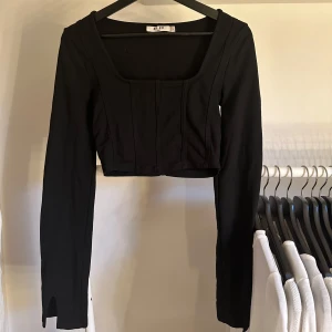 Svart kort tröja - Svart magtröja med fyrkantig urringing samt utsvängda ärmar.