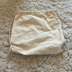 Beige gympapåse - Säljer en enkel och praktisk beige gympapåse med dragsko. Perfekt för att snabbt packa ner träningskläder eller andra småsaker. Lätt att bära med sig tack vare de smidiga snörena.💗💗