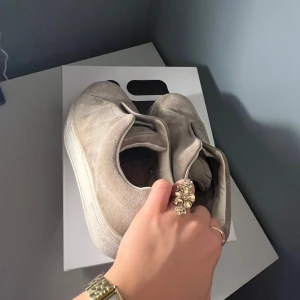 Gråa sneakers från Eytys - Säljer ett par gråa sneakers från Eytys med en stilren design. Skorna har en bred vit sula och en mörklila detalj på hälen. Nypris är 2 099kr men de är väl använda så lägger därför ut de för 700kr(låda kommer med)💕
