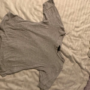 Grå t-shirt från H&M  - En enkel och bekväm grå t-shirt med korta ärmar. Perfekt för en avslappnad stil. T-shirten har en rund halsringning och är tillverkad i ett mjukt material.från H&M 