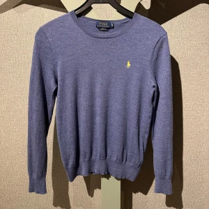 Blå tröja från Polo Ralph Lauren - Säljer en stilren blå tröja från Polo Ralph Lauren i merinoull. Etiketten säger M men är liten i storlek. Perfekt för en elegant och avslappnad look.🔥              OBS! Igensytt hål i bakre krage.