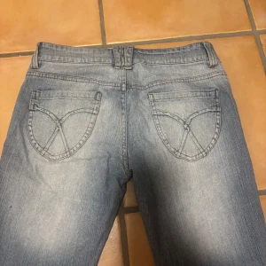 Blå jeans med tryck på bakfickan - Snygga ljusblå jeans med broderade detaljer på bakfickorna. Mått står på bilden🩷