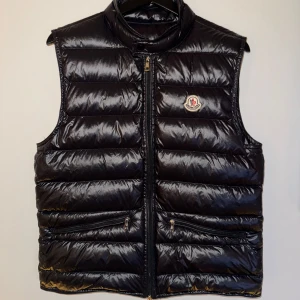 Moncler gui väst  - Snygg svart väst från Moncler. Perfekt till våren och ger en stilren look. Storlek 1 vilket motsvarar S 