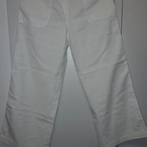 Vita byxor från Grain de Malice - Säljer ett par vita byxor från Grain de Malice. Byxorna har en vid passform och är tillverkade i ett bekvämt material. Perfekta för en stilren look.