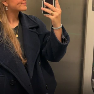 Mörkblå kappa Zara - Säljer en stilren mörkblå kappa med stora knappar och bred krage. Perfekt för kyligare dagar och ger en elegant look. Passar bra till både jeans och klänning.