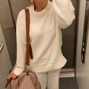 Vit stickad tröja - Säljer en mysig vit stickad tröja med långärmad design. Perfekt för kyligare dagar och ger en stilren look. Tröjan har en enkel och klassisk stil som passar till många olika outfits.