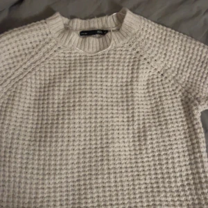 Vit stickad tröja från 157 - Mysig vit stickad tröja från 157 i storlek XS. Tröjan har en texturerad yta och långa ärmar, perfekt för kyligare dagar. Den har en rund halsringning och ribbade kanter för extra komfort.