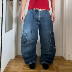 Blå baggy cargopants - Säljer ett par blå baggy cargopants med stora fickor på sidorna. Byxorna har en lös passform och är perfekta för en avslappnad stil. De har en klassisk cargodesign med flera fickor och en bekväm midja. 