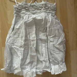 Ljusblå klänning med pärldetaljer - Kort puffig ljusblå klänning från primark aldrig använd. En brun pärla har lossnat, se bild. Super söt🤍