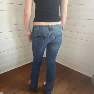 Blå jeans med bootcut - Snygga blå jeans med bootcut-stil och låg midja. Perfekta för en avslappnad look. Klassisk femficksdesign med subtila detaljer på bakfickorna.