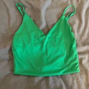 Grön linnetopp  - Snygg grön linnetopp från Amisu med smala axelband och v-ringning. Perfekt för varma dagar. Tillverkad i ett mjukt och bekvämt material.