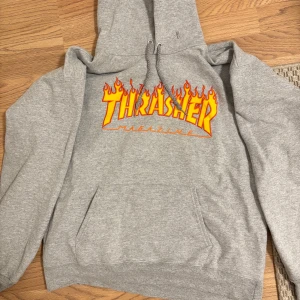  Thrasher hoodie - Säljer en grå hoodie från Thrasher Tröjan har en stor ficka framtill och justerbar huva med snören. Perfekt för en skate stil. Säljer pga min styl. Storlek är M så passar väl för 170. Köpte för ungefär 1300 i Junkyard