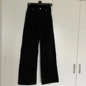 Svarta manchesterbyxor - Snygga svarta manchesterbyxor med hög midja och vida ben. Byxorna har klassiska femficksdetaljer och knappar i silverfärg. Perfekta för en stilren look.