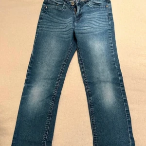 Blå jeansbyxor från Pepperts - Säljer ett par klassiska blå jeansbyxor från Pepperts i storlek 140. Byxorna har en dragkedja och knapp framtill samt fickor både fram och bak. Perfekta för barn i åldern 9-10 år.