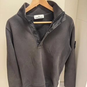 Grå tröja från Stone Island - Säljer en stilren grå tröja från Stone Island med dragkedja och knappar vid halsen. 