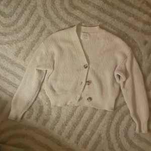 Vit ribbad kofta från Zara - Säljer en stilren vit ribbad kofta från Zara i storlek 9-10 år. Koftan har en v-ringad design med knappar framtill och långa ärmar. Perfekt för en mysig och trendig look. Passar bra till både jeans och kjol! ❤️