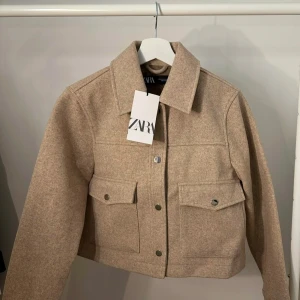 Soft short jacket - Zara  - Snygg beige jacka från Zara med knappar framtill och två stora fickor. Jackan har en klassisk krage och är perfekt för höst och vår - mjuk och skönt material! (Obs! Har på mig kortmidjade byxor på bilden) 