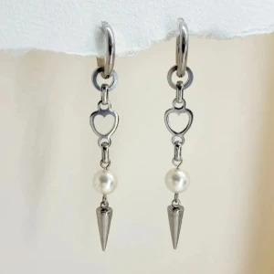 Silverörhängen med hjärta och pärla - Stilrena silverörhängen med hjärtformad detalj och hängande pärla. Handgjorda örhängen●Material- 100% rostfritt stål och pärlor ●Örhängeskrokar -rostfritt stål. Nickel fri. Längd -7cm.Vattentåliga, ändrar inte färgen! 