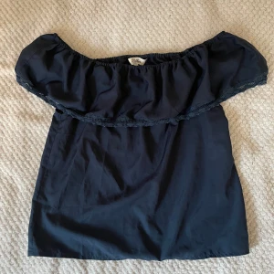 Svart offshoulder topp från Ribbon - Snygg svart offshoulder topp från Ribbon med volangdetalj och elastisk band. Har vanligtvis storlek S i toppar, den är lite stor på mig (Köparen står för fraken!)
