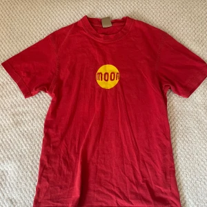 Röd t-shirt från Moon Climbing - Säljer en tshirt från Moon Climbing med ett gult tryck på bröstet. Tshirten är urtvättad men inga större skador/defekter utöver det. (köparen står för frakten!)