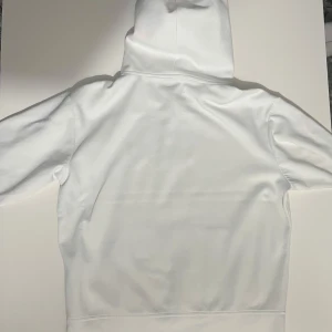 Vit hoodie från Ralph Lauren - Säljer en stilren vit hoodie från Ralph Lauren med dragkedja och den klassiska loggan på bröstet. 