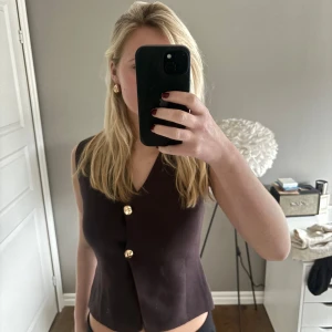 Brun väst från Zara - Snygg brun väst från Zara med guldknappar och v-ringad design. .