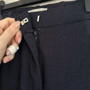 Blå  prickiga byxor från H&M - Snygga blå  byxor med vita prickar från H&M. Byxorna har en dragkedja och en diskret knäppning framtill. Perfekta för en stilren look med en touch av mönster.