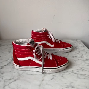 Röda sneakers från Vans - Snygga röda sneakers från Vans med vit sula och klassisk sidostrip. Skorna har snörning och är tillverkade i mocka. Perfekta för en cool och avslappnad stil. Storlek 38.5