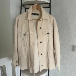 Beige manchesterjacka från Zara - Säljer en snygg beige manchesterjacka från Zara. Jackan har långa ärmar och knappar framtill samt två bröstfickor med knappar. Perfekt för en stilren look.