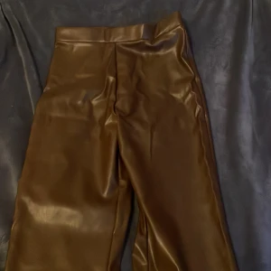 Bruna skinnbyxor - Snygga bruna skinnbyxor med hög midja och en stilren design. Perfekta för att ge din outfit en edgy touch. Passar bra till både vardag och fest.