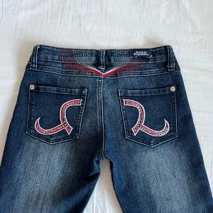Coola jeans!! från Victoria Beckham rock&rebublic - Så snygga jeans med design på både bak och framsida💗 från Victoria Beckham for rock&republic. De är i fint skick, en mindre slitning på designen där framme. Bootcut, low/mid rise. Innerbenslängd 72cm, midjemått 35cm