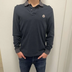 Moncler pike långärmad  - Säljer denna snygga mörkblåa långärmade piké med gråa detaljer som krage med bra skick. Kontakta för fler bilder eller för mer information! 
