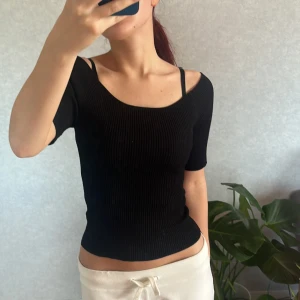 Svart ribbad topp - Säljer en svart ribbad topp med korta ärmar och en offshoulder-design. Används ett par gånger men är annars precis som ny🤍