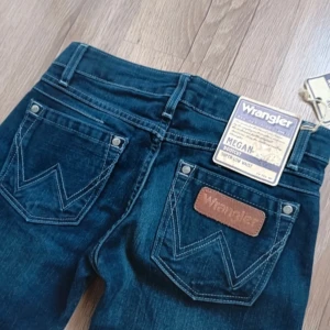 Wrangler jeans - Helt nya jeans med prislappar från Wrangler! Modellen är superlåg midja och bootcut i en så snygg blå färg. Storlek 25/34 och midjemåttet syns på bilden💕