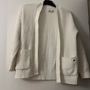 Stickad kofta  - Säljer en vit creme färgad stickad kofta från Hollister i storlek xs! Perfek inför hösten och vintern! Koftan är sällan använd och i mycket bra skick!