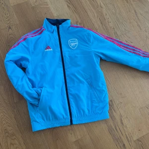 Arsenaljacka - Jacka för barn. Adidas. Arsenal. Går att vända ut och in för olika utseende. Regnskydd. Aldrig använd.