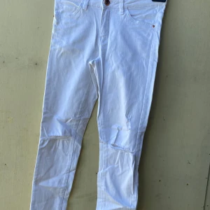 Vita byxor med fickor - Säljer ett par vita byxor i storlek 152. De har en klassisk design med fickor både fram och bak. Perfekta för en stilren look!
