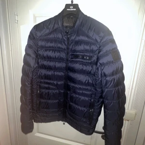 Belstaff padded down jacket - Vi säljer nu denna fina höstjacka från Belstaff. Storlek: 50 Pris: 1966:- Retail 4499:- Skick: 9/10 knappt använd Modellen är ca 190cm och väger ca 70kg Hör av er vid frågor eller funderingar!