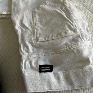 Vita jeans från Denim - Säljer ett par snygga vita jeans från Dr.Denim. De har en klassisk femficksdesign med knappar och dragkedja framtill. Perfekta för en stilren look. Används 1 gång