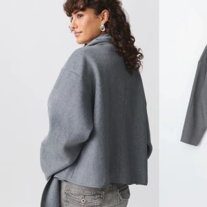 Grå short scarf jacket från Ginatricot  - En grå kort kappa. Med tillhörande scarf till som går att ta bort om man vill . Jackan är helt ny och oanvänd. Jackan passar xxs-s. 