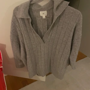 Trekvartsärmad stickad tröja  - Stickad tröja med korta ärmar från H&M och liten krage. Använd ett fåtal gånger och i jättebra skick. 