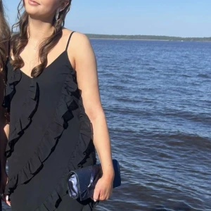 svart volangklänning - svart lång volangklänning, använd en gång och är i fint skick! har bara volanger på framsidan och är justerbar i axelbanden. jag är 170, skriv privat för fler och bättre bilder.