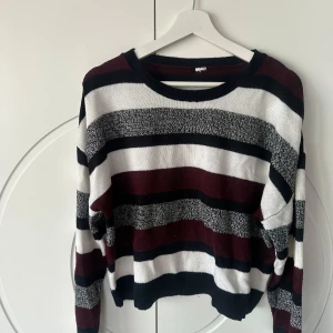Randig stickad tröja - Säljer en supermysig stickad tröja med breda ränder i vinrött, svart, vitt och grått. Perfekt för höst och vinter! Tröjan har en avslappnad passform och långa ärmar, vilket gör den idealisk för kyliga dagar. Den är i bra skick och redo för en ny ägare. 🖤🤍