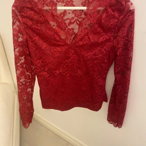 Röd spetsblus från Shein - Snygg röd spetsblus från Shein med omlott-design och v-ringning. Blusen har långa ärmar och ett vackert blommigt mönster. Perfekt för en elegant look.