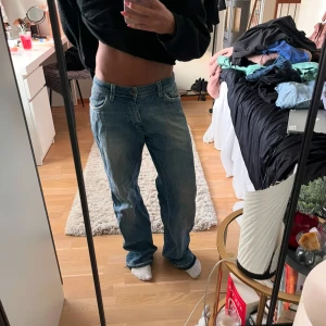 Blå baggy jeans - Säljer ett par blå jeans med en avslappnad passform och slitna detaljer vid fållen. Perfekta för en casual look. De har en klassisk femficksdesign och är tillverkade i ett robust denimtyg.