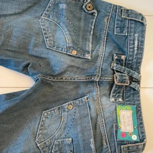 lågmidjade bootcut jeans - supersnygga lågmidjade jeans med lite coola detaljer, jag har köpt jeansen här på Plick men de kommer inte till användning då de tyvärr var för små för mig. midjemåttet rakt över är 37/38 och innebenslängden är 79/80. använd gärna köp nu.  (lånade bilder från förra ägaren)